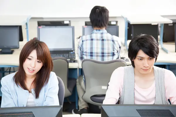 young asian students working on computers in classroom