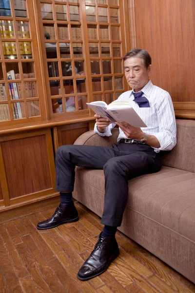 mature businessman reading book in room