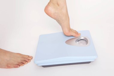 Mavi terazide duran bir kadının bacakları.