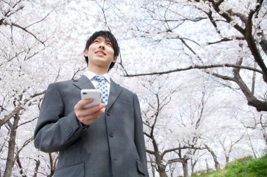 Parkta cep telefonu kullanan Asyalı işadamı 