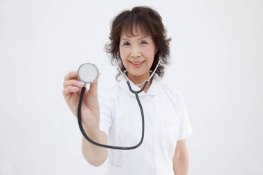 Beyaz arka planda steteskop tutan Asyalı olgun doktor.