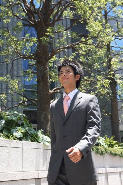 Takım elbiseli ve kravatlı bir adam kaldırımda yürüyor.