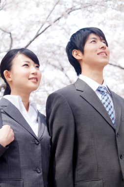 Bahçede kiraz çiçekleri olan Asyalı çift.