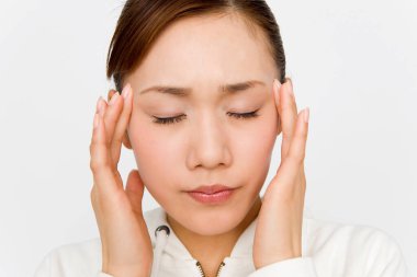 Güzel Asyalı kadın şakaklarına dokunuyor. Beyaz bir geçmişi var ve baş ağrısı çekiyor..