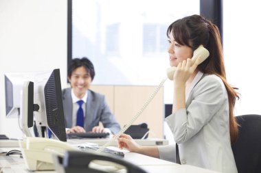 Masada otururken telefonla konuşan bir kadın.