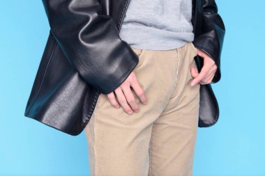 Mavi arka planda siyah ceketli genç adam..