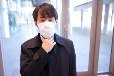 Maske takan Asyalı iş adamı. 