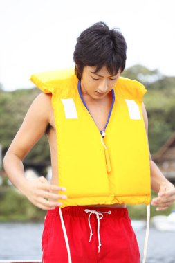 Sarı yelekli Asyalı adam.