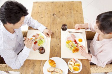 Çiftler kahvaltıda taze meyve ve ekmek yiyor.