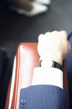 Kol saati olan, sandalyeye oturan iş adamı elini kapat. 