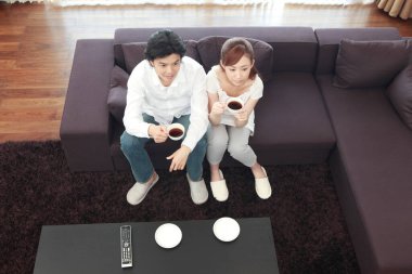 Bir çift kanepede oturup kahve içiyorlar.