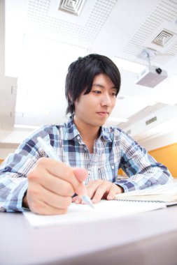 Asyalı öğrenci sınıfta ders çalışıyor.