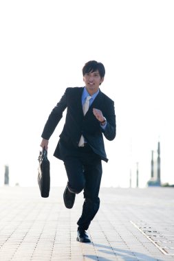 Genç Asyalı sokakta koşuyor. 