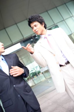 İki genç Asyalı iş adamı şehir ortamında poz veriyor.