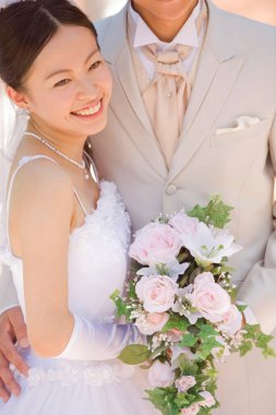 Dışarıda poz veren mutlu Asyalı bir çift yeni evli.