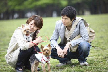 Bir adam ve bir kadın köpeklerin önünde diz çöküyor.