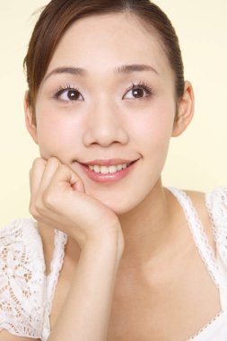 Genç, güzel Asyalı bir kadın beyaz arka planda yalnız gülümsüyor. 