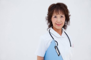 Beyaz arka planda steteskobu olan Asyalı olgun bir doktor.