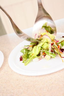Taze metal çatal bıçaklı salatayı beyaz tabağa koy.