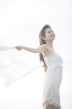 Sahilde beyaz elbiseli Asyalı kadın. 