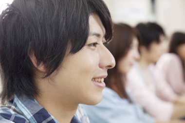 Genç Asyalı öğrenciler sınıfta bilgisayarlar üzerinde çalışıyorlar.