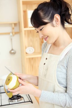 Mutfakta elma soyan Asyalı kadın.