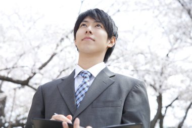 Şehir parkında not defteri olan Asyalı iş adamının portresi.