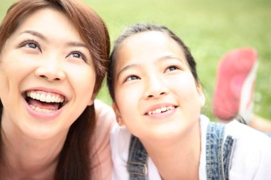 Asyalı anne ve kızının parkta dinlenme portresi.