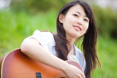 Doğada Guiter çalan Asyalı kadın 