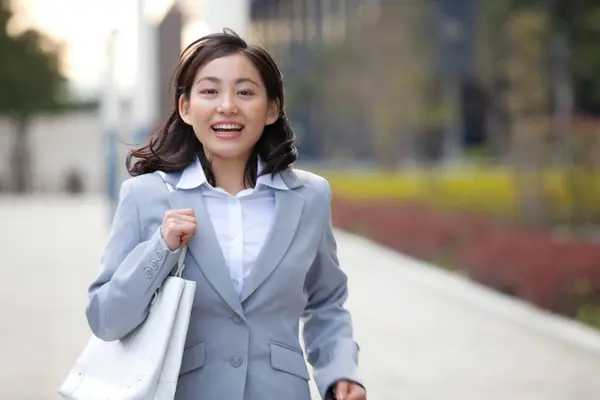 a woman in a business suit walking down a sidewalk