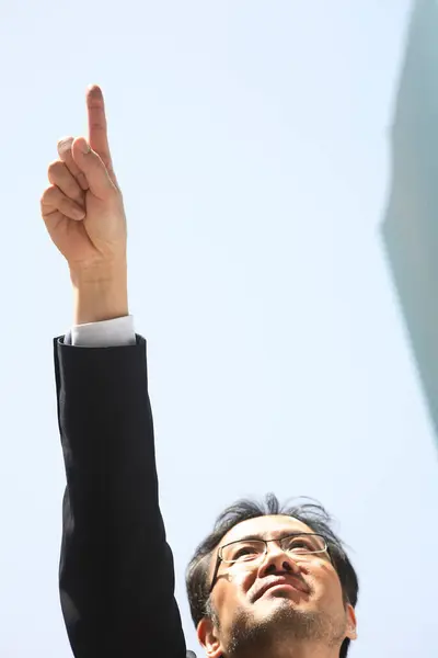businessman raising arms in front of the sky