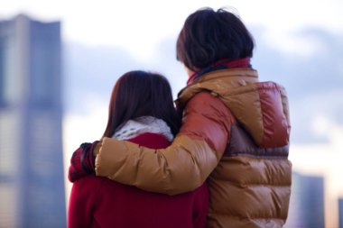 Kış kıyafetleri içinde şehre bakan arka plan bulanık bir çift. 