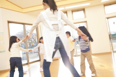 Öğretmenle çember oyunu oynayan çocuklar