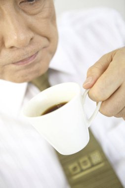 Asya 'lı kıdemli iş adamı elinde çay tutuyor.