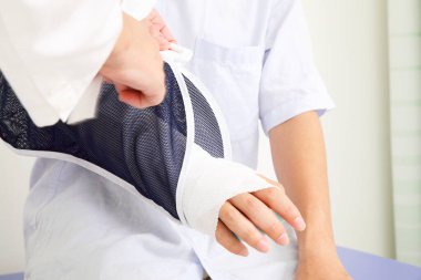 Tedavi ve iyileşme sürecinde hastaya kol askısında yardım eden doktor..