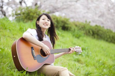 Parkta gitar çalan güzel genç bir kadın.