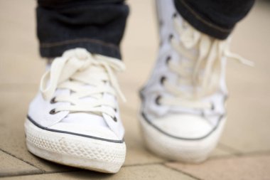 İnsan ayağındaki beyaz spor ayakkabıları kapatın.