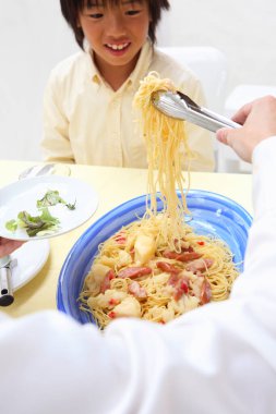 Babası tarafından spagetti servis edilen mutlu bir Asyalı çocuğun portresi. 