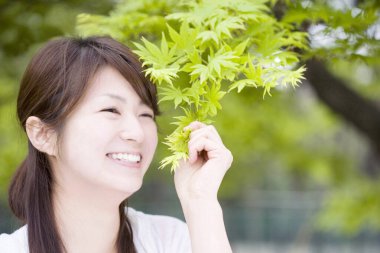  Parktaki ağaç yapraklı Asyalı kadın.