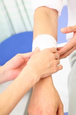 Hemşire erkek eline bandaj yapıyor.