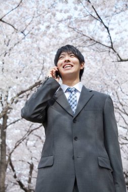 Bahçede akıllı telefonu olan Asyalı iş adamı