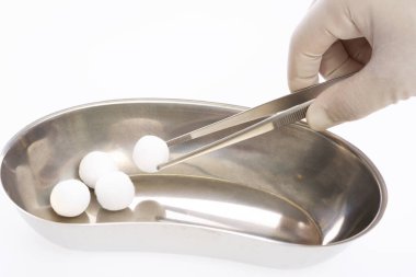 Doktorun eli tepsiden pamuk pedleri alıyor. 