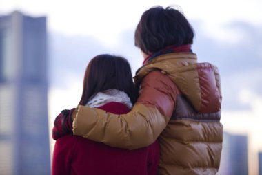 Kış kıyafetleri içinde şehre bakan arka plan bulanık bir çift. 