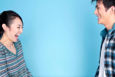 Mavi arka planda gülen mutlu genç çiftin portresi.