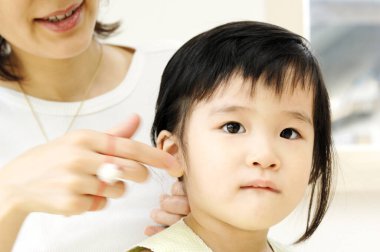 Genç bir kadın küçük kızına kuaförlük yapıyor. 