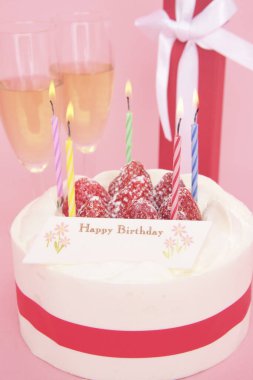 Mumlu doğum günü pastası ve taze çilekler ve şampanya ile bardaklar.