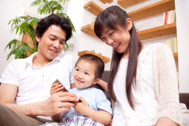 Evdeki kanepede akıllı evlerle oynayan mutlu bir aile.