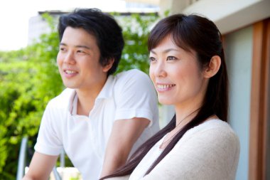 Balkonda duran Asyalı genç bir çiftin portresi. 