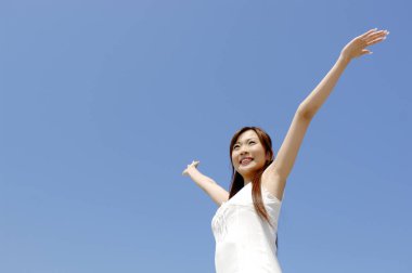 Mavi gökyüzüne karşı ellerini kaldırmış genç bir kadın..