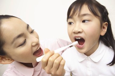 Japon kadın dişçi şirin küçük kıza diş fırçalamayı öğretiyor.